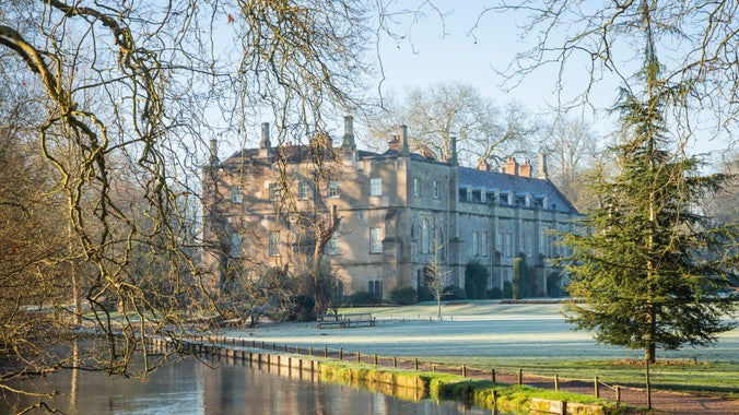Garden with river in foreground and house in background in winter, Mottisfont, Hampshire